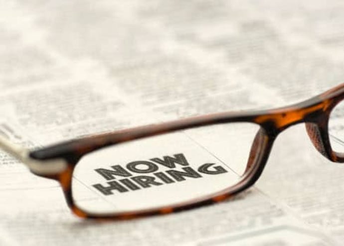 Now Hiring classified ad showing through reading glasses.