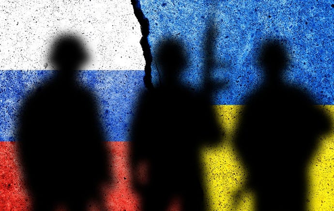Flag of Russia and Ukraine painted on a wall with soldiers' shadows.