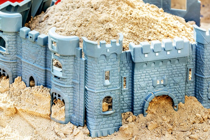 Photo of a toy fortress stuffed with sand set up in a sandbox on a sunny day