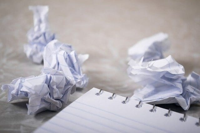 Crumpled up paper next to a notepad.