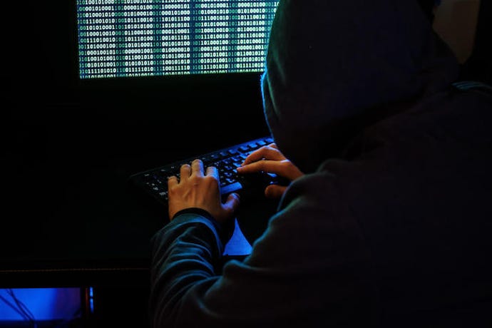 Hooded hacker on a laptop.