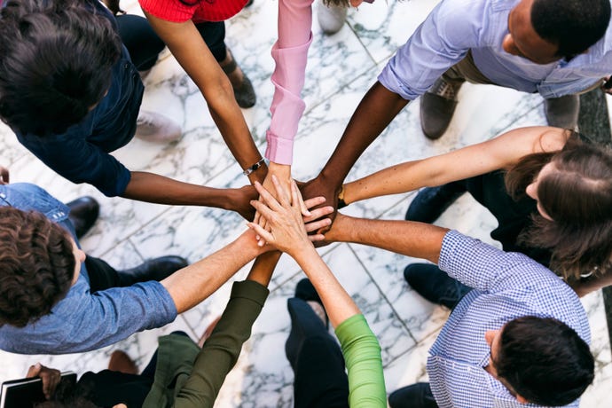 A Diverse group of people holding their arms out together as a Team.
