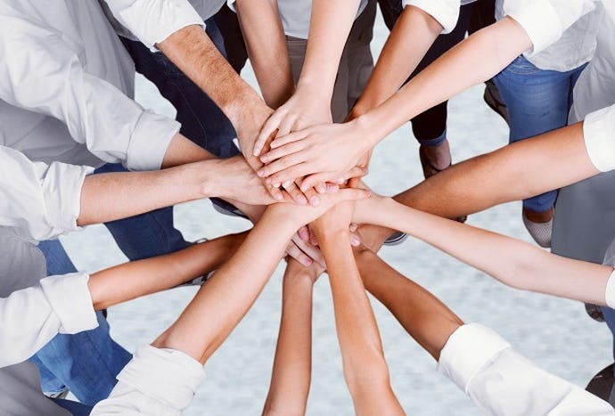 Top-down photo of a group of businesspeople putting their hands together in a group circle show of team spirit