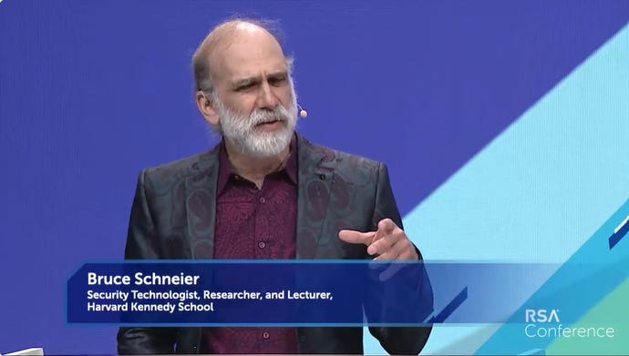 Bruce Schneier, a man with a short white beard, wears a purple-and-black patterned suit as he presents at RSAC 2022