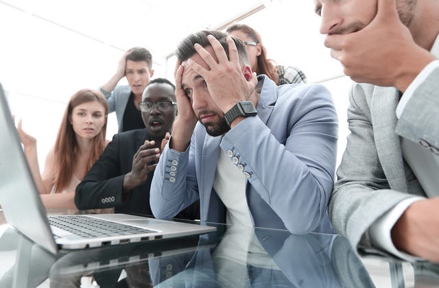 People gathered around a computer looking stressed