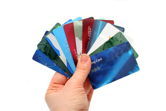 A pale man's hand grips a fanned-out stack of debit or credit cards