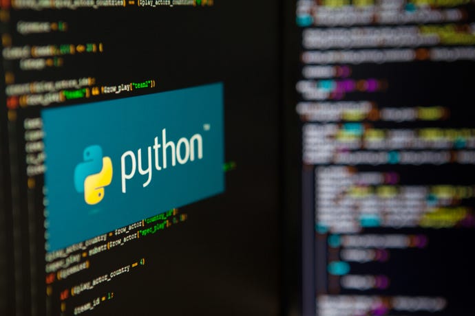 python software logo on a laptop against background of computer code