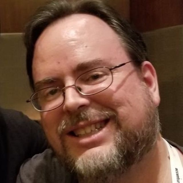 Steve Christey Cole, who catalogs CVE bugs, has a short light-brown beard and copper-framed glasses. He's smiling.