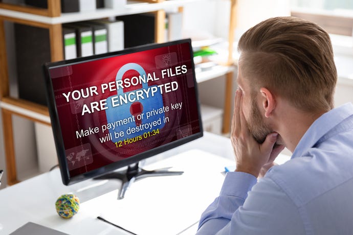 Man sitting in front of computer with ransomware notice