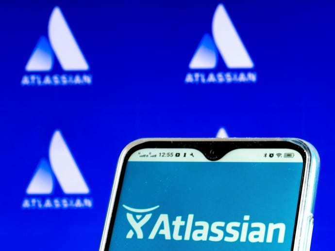 Image of an Atlassian app on a mobile phone in front of a backdrop with the company logos