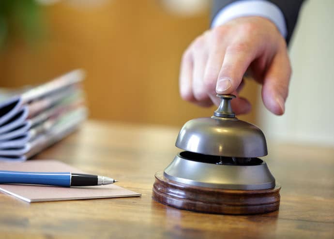Hand ringing a hotel reception service bell to attract attention