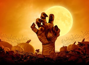 Scary zombie hand breaking through the ground of a graveyard. Pumpkin in the background. 