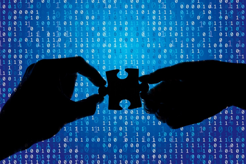 Silhouette of a hands holding a jigsaw puzzle piece with binary background.