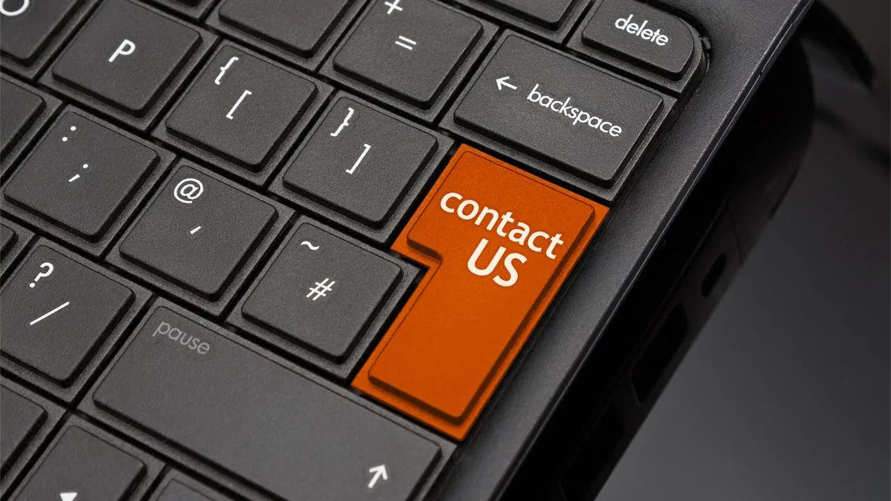 Laptop keyboard with dark keys and an orange key reading 'Contact Us' Laptop keyboard with dark keys and an orange key reading 'Contact Us'