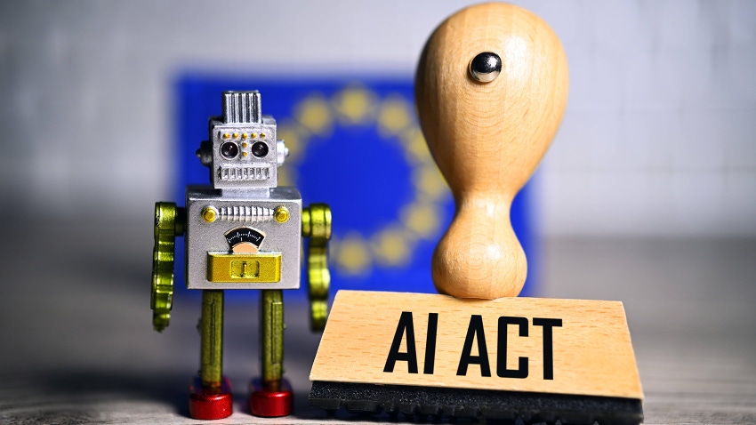 miniature robot and stamp with the inscription AI Act in front of a European flag