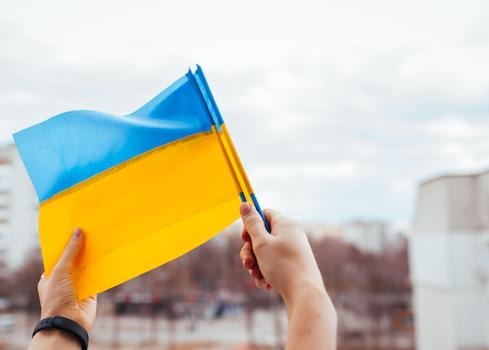 Hands hold a small Ukrainian flag