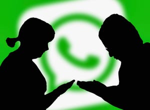 Silhouettes of people holding smartphones using the WhatsApp instant messaging app.