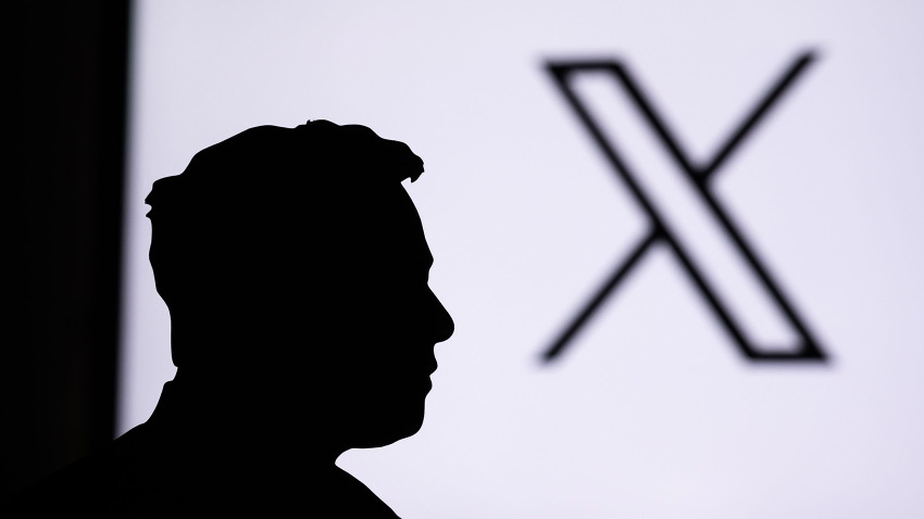 Silhouette of businessman Elon Musk, New logo of Twitter in background.