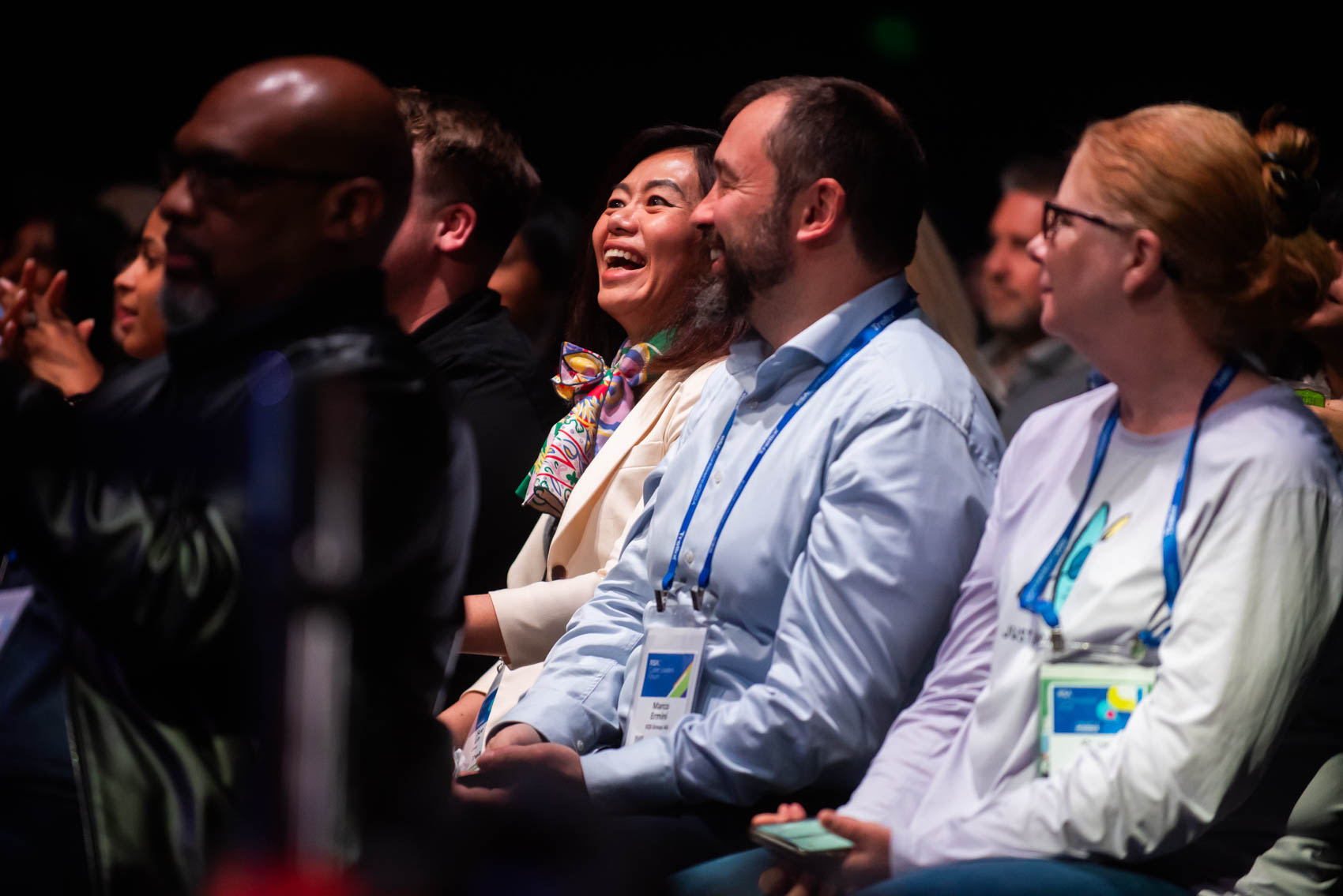 يضحك الحاضرون في المؤتمر ويصفقون أثناء وقوف أحد الفنانين على المسرح.