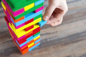 Close up of a hand pulling a colorful jenga block from a big pile. Close up of a hand pulling a colorful jenga block from a big pile.