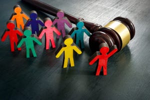 different brightly colored figures stand on table, beside a gavel. One raises its hand, indicating it is speaking up for the rest. Represents advocacy
