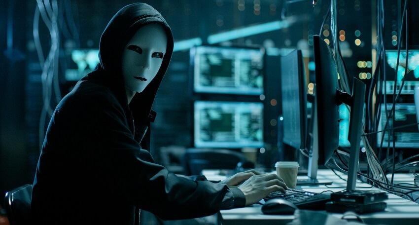 Masked Hacker is Using Computer for Organizing Massive Data Breach Attack on Corporate Servers. They're in Underground Secret Location