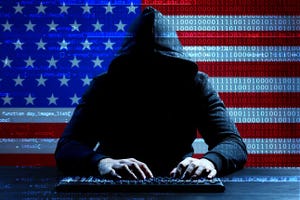 Hacker working with keyboard at table and USA flag on background.