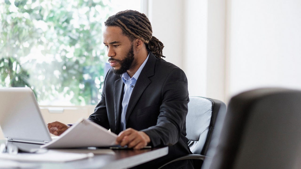Concentrated businessman working with laptop at desk in office Concentrated businessman working with laptop at desk in office
