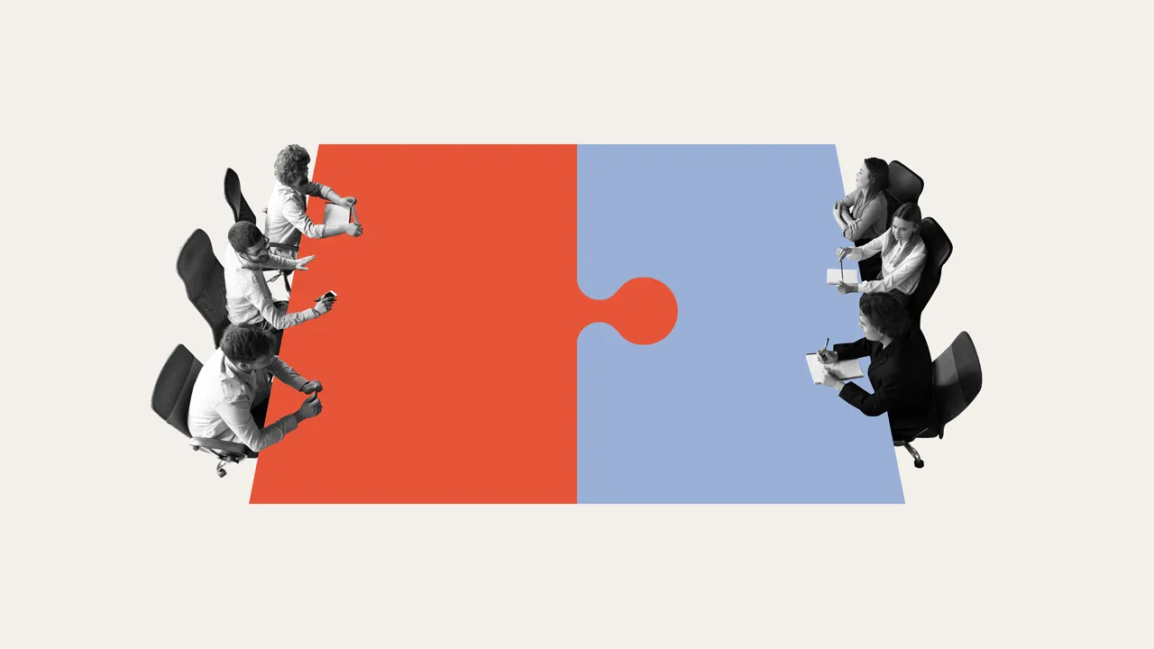 Business teams sit on each side of a puzzle table Business teams sit on each side of a puzzle table
