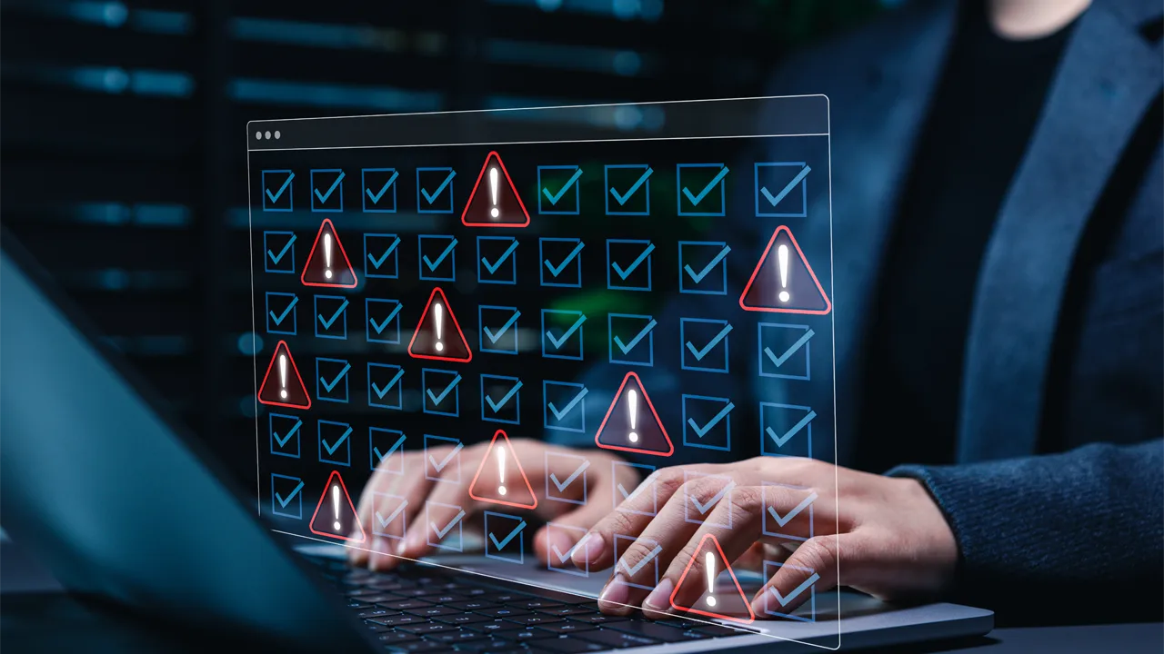 A user at a laptop, with an illustrated overlay of checkmarks and security alert icons A user at a laptop, with an illustrated overlay of checkmarks and security alert icons