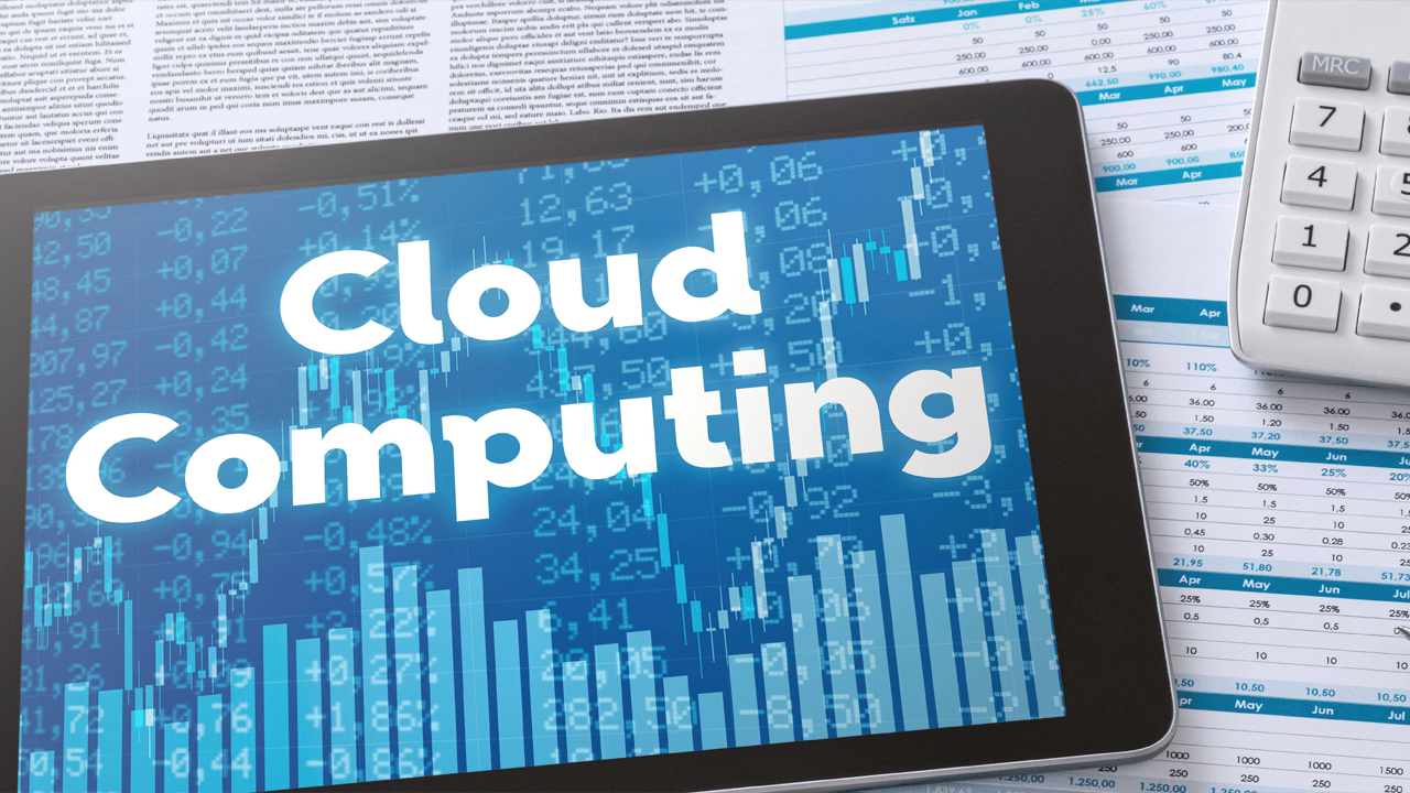 A tablet with the words 'Cloud Computing' sits on financial documents A tablet with the words 'Cloud Computing' sits on financial documents