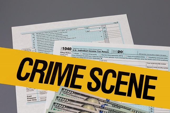 1040 individual income tax return with crime scene tape. Identity theft, tax fraud and cybercrime concept