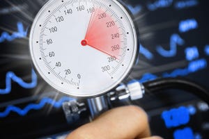 High blood pressure on the gauge against the background of the cardiac monitor. 