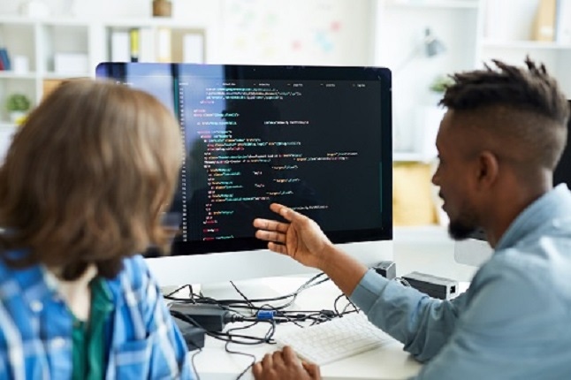 two software developers discussing a project sitting at a computer