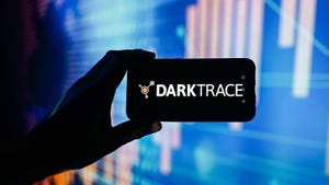 In this photo illustration a Darktrace logo is displayed on a smartphone with stock market percentages in the background.