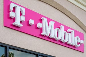 White and pink T-Mobile sign hangs on tan building