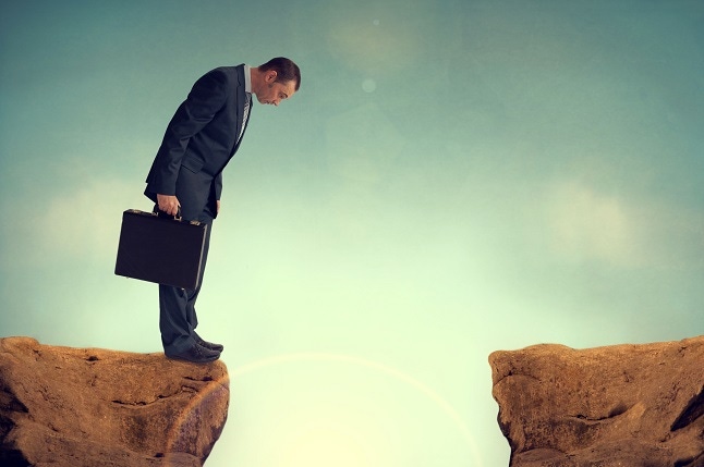 Businessman on the edge of a cliff looking down.