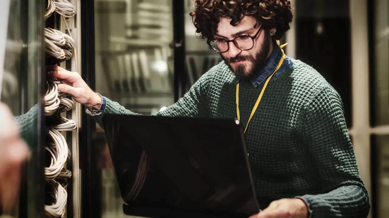 An IT worker in a data center, on a laptop An IT worker in a data center, on a laptop