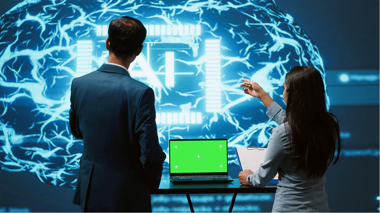 Two IT experts in front of a screen with the letters AI over the digital image of a brain Two IT experts in front of a screen with the letters AI over the digital image of a brain