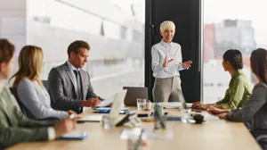 An executive meets with other executives in a boardroom An executive meets with other executives in a boardroom