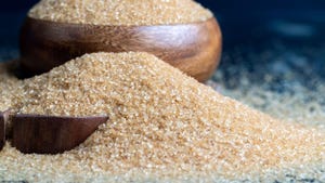 Brown crystalline sugar from cane, poured into a bowl and on the table sugar from brown cane Brown crystalline sugar from cane, poured into a bowl and on the table sugar from brown cane
