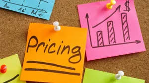 An orange sticky note reads 'Pricing," surrounded by pricing models on other stickies An orange sticky note reads 'Pricing," surrounded by pricing models on other stickies