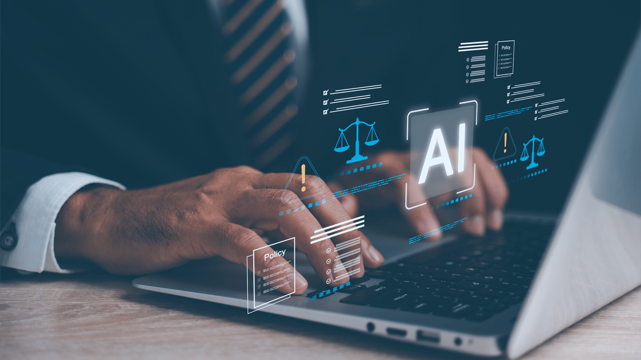 An IT executive works at a laptop with AI icons highlighting responsible technology governance An IT executive works at a laptop with AI icons highlighting responsible technology governance
