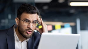 Perplexed businessman in glasses looking at laptop screen in office, showing confusion Perplexed businessman in glasses looking at laptop screen in office, showing confusion
