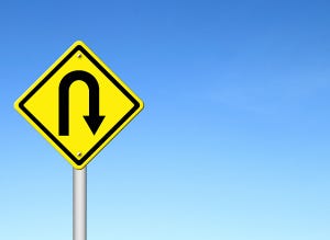 Yellow U-turn sign on background of blue sky