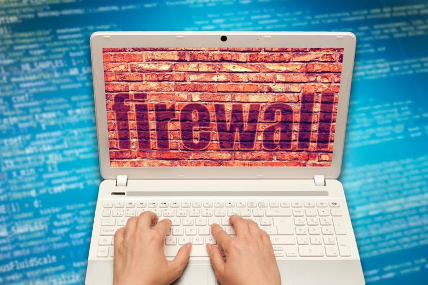 laptop open with a brick background that spells out firewall