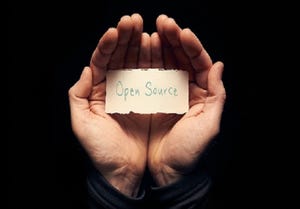 hands holding a small sign that says open source in a dark room