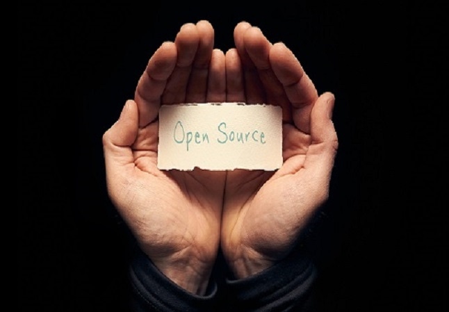 hands holding a small sign that says open source in a dark room