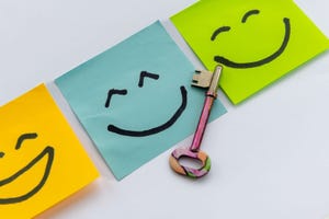 A key to happiness concept with a key and hand drawn happy faces isolated in a white background.