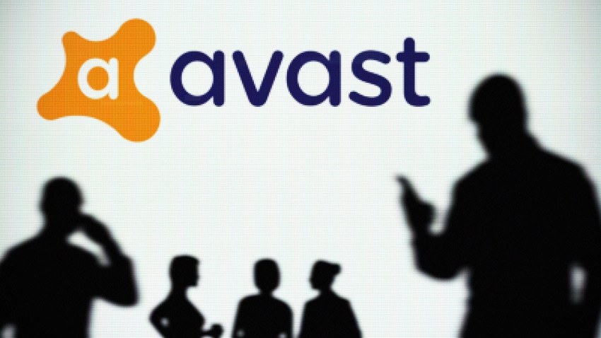 The Avast logo is seen on an LED screen in the background while a silhouetted person uses a smartphone.